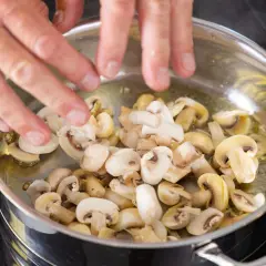 Ręce mieszają pokrojone pieczarki na patelni z olejem. Czy pieczarki są zdrowe? Tak, to pyszny i zdrowy dodatek!