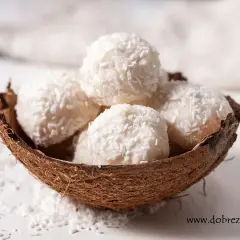 Pięć białych kulek Raffaello w łupinie kokosa, posypanych wiórkami. Idealne na deser, ale warto sprawdzić Raffaello kcal przed zjedzeniem.