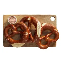 Trzy świeże precle z solą na drewnianej desce. Zastanawiasz się nad precel Lidl kcal?