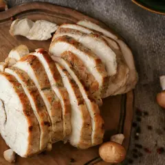 Pokrojona pierś z indyka na desce, obok czosnek i pieczarki. Zdrowe danie, które pozwoli Ci kontrolować pierś z indyka kcal.