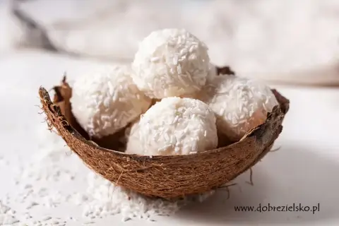 Pięć białych kulek Raffaello w łupinie kokosa, posypanych wiórkami. Idealne na deser, ale warto sprawdzić Raffaello kcal przed zjedzeniem.