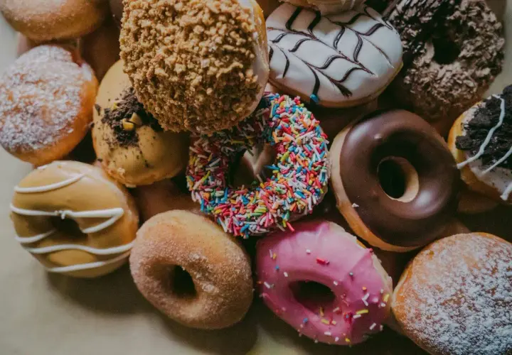 Kolorowe pączki z posypką, lukrem i cukrem pudrem. Każdy pączek to mała przyjemność, ale warto pamiętać o jego pączek kcal.