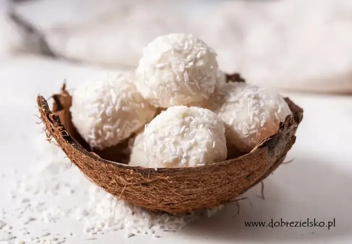 Pięć białych kulek Raffaello w łupinie kokosa, posypanych wiórkami. Idealne na deser, ale warto sprawdzić Raffaello kcal przed zjedzeniem.