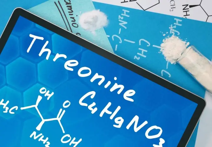 Tablet z napisem "Threonine" i wzorem chemicznym. Obok proszek w probówce i na kartce.