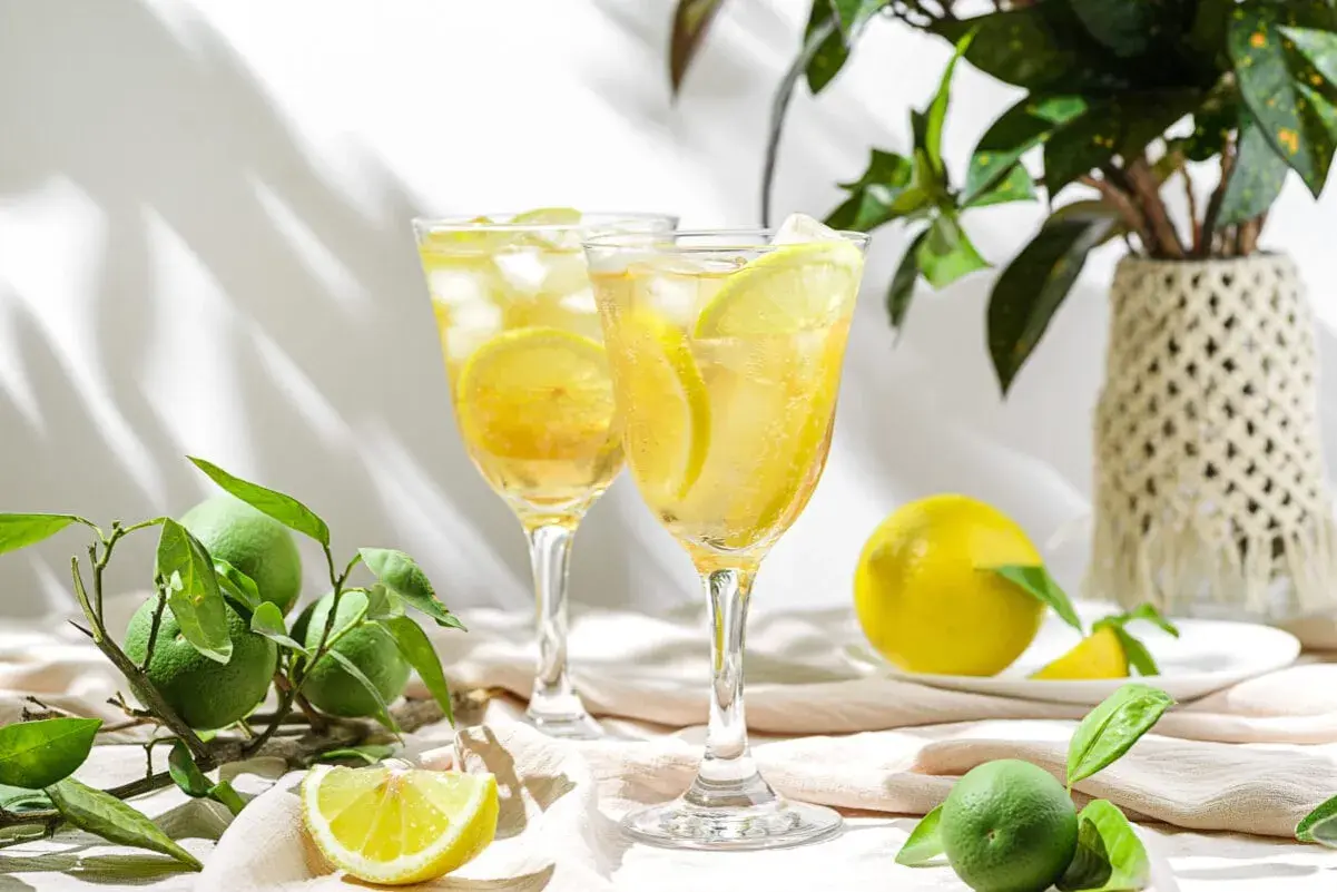 Dwa orzeźwiające limoncello spritz z plasterkami cytryny i lodem, otoczone świeżymi owocami cytrusowymi.