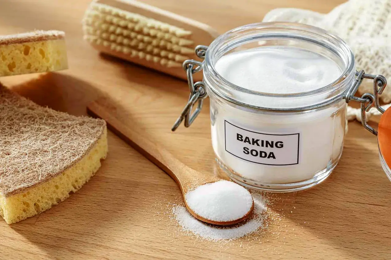 Słoik z sodą oczyszczoną i łyżka z proszkiem. Soda oczyszczona ma właściwości bakteriobójcze, idealna do sprzątania.