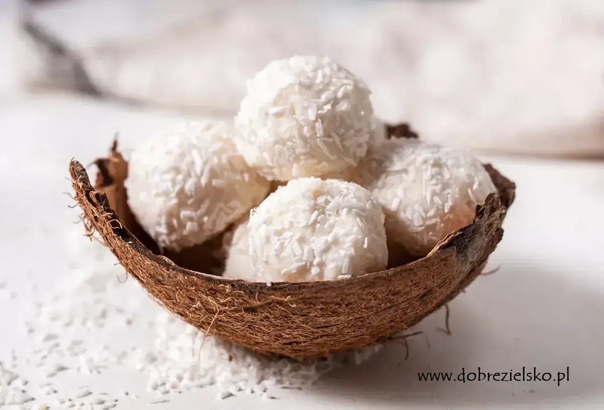 Pięć białych kulek Raffaello w łupinie kokosa, posypanych wiórkami. Idealne na deser, ale warto sprawdzić Raffaello kcal przed zjedzeniem.